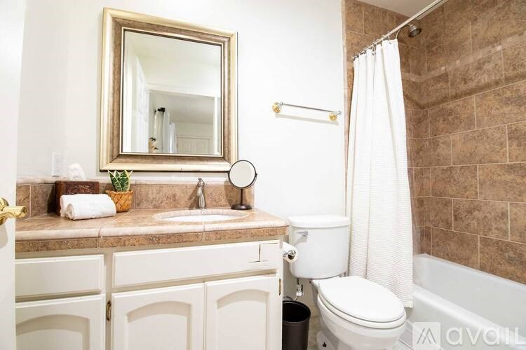 A bathroom with a white toilet, a sink with a mirror above it, and a shower area.