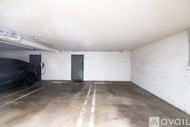 A white wall with a door and a car parked in a garage.