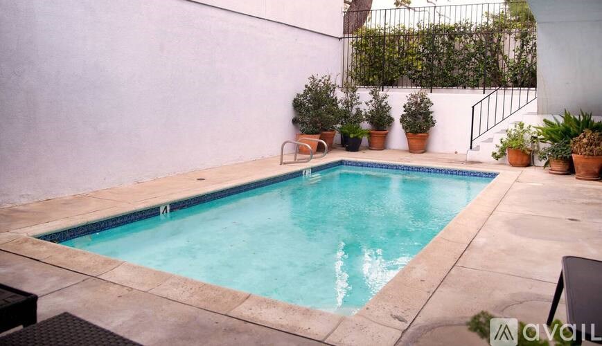 A small pool with a black metal railing and a white wall.