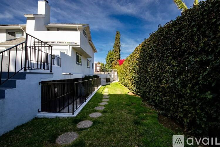 A white house with a balcony and a garden with stepping stones.