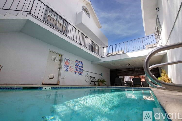 A pool in a residential area with a balcony and a small garden.