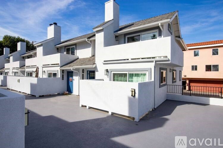 A white modern house with a balcony and a blue door.