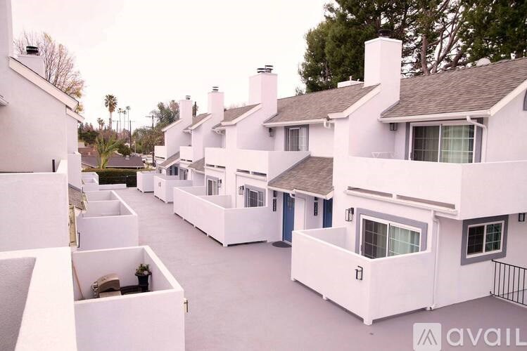 A row of white houses with a balcony on the front.