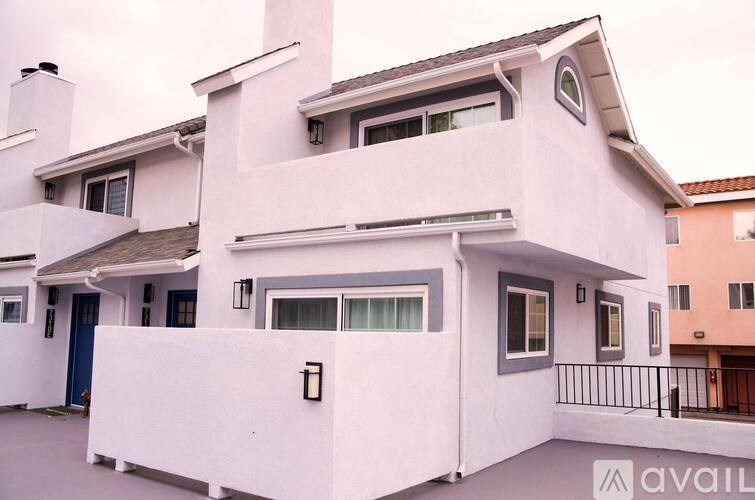 A white two-story house with a balcony on the second floor.