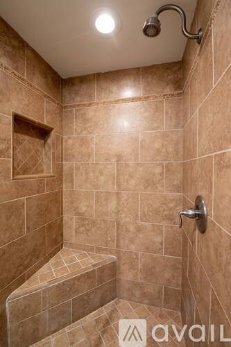 A tiled shower with a bench seat and a shower head.