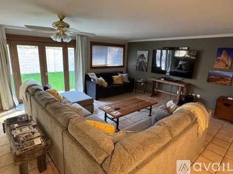 A living room with a large couch and a ceiling fan.