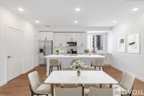 A white dining table with chairs is set up in a modern kitchen.