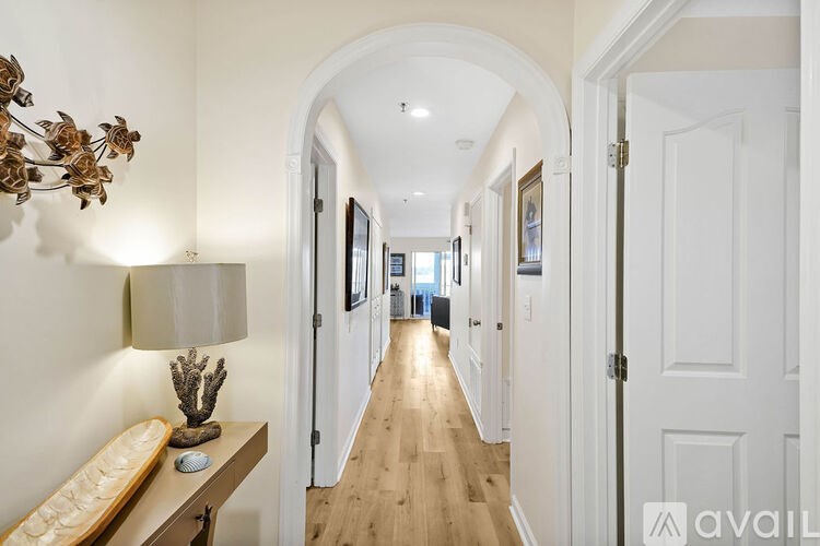 A long hallway with white doors and a bench with a cactus on it.