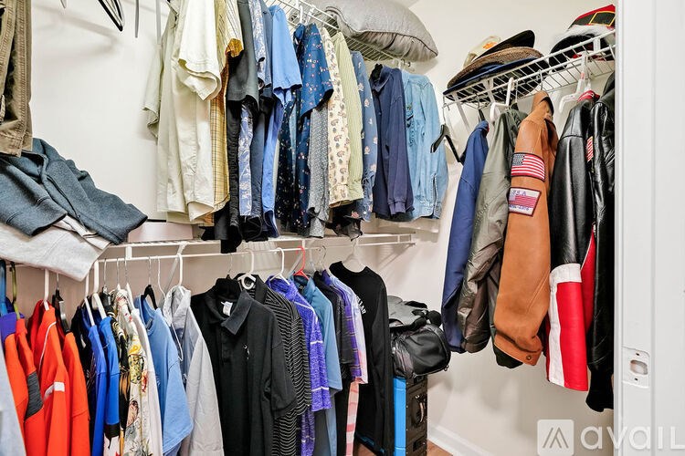 A closet full of clothes hanging on a white shelf.