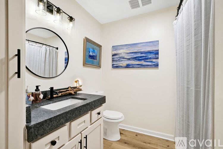 A bathroom with a toilet, sink, and a painting on the wall.