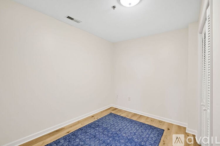 A room with a blue rug on the floor and a white wall.