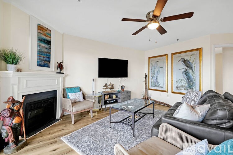 A living room with a fireplace, a couch, a chair, a coffee table, and a ceiling fan.