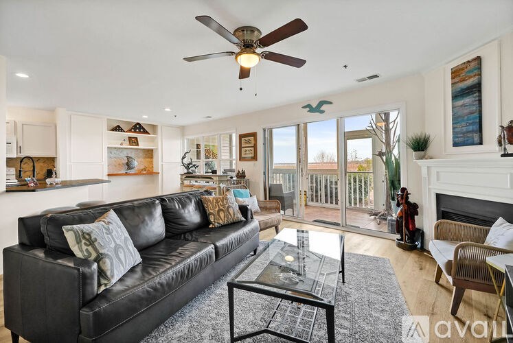 A living room with a black leather couch and a glass coffee table.