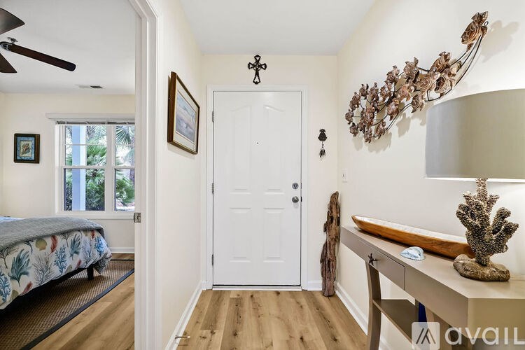 A room with a bed, a table, a lamp, and a painting on the wall.