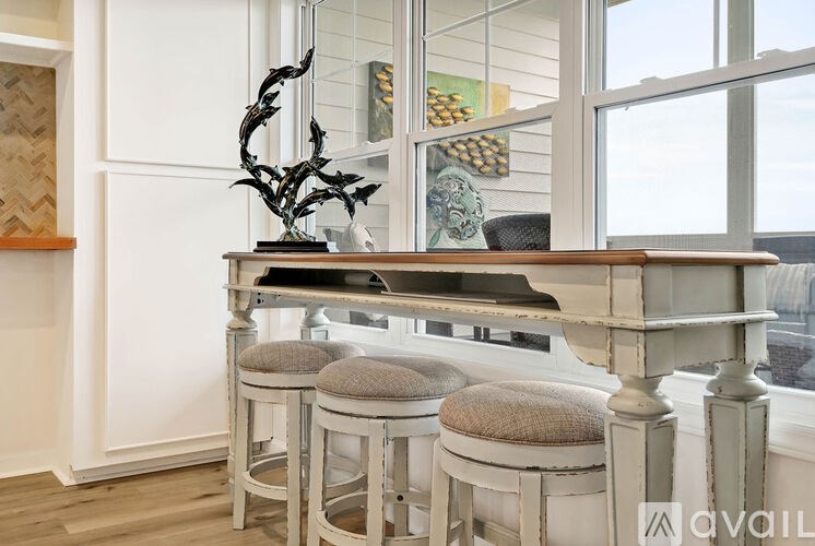 A bar with three stools in front of a window.