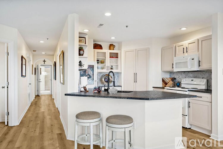 A kitchen with white cabinets and a black countertop.
