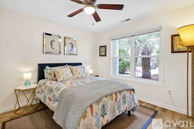 A bedroom with a bed, a ceiling fan, and a window showing an outdoor view.