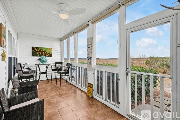 A balcony with a table and chairs overlooking a field.