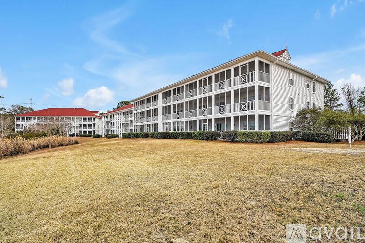 A large white building with a red roof and balconies is surrounded by a grassy area.