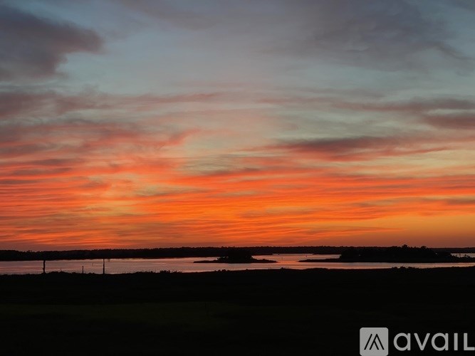 A beautiful sunset over a body of water with a bridge in the distance.