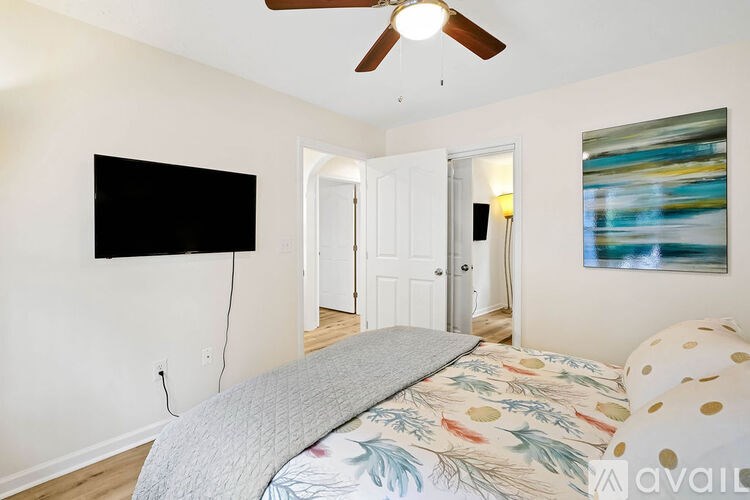 A bedroom with a bed, a ceiling fan, and a painting on the wall.