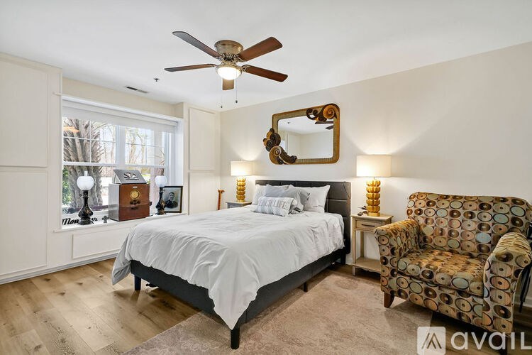 A bedroom with a bed, chair, and mirror.