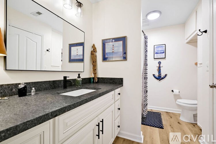 A bathroom with a sink, mirror, toilet and shower.