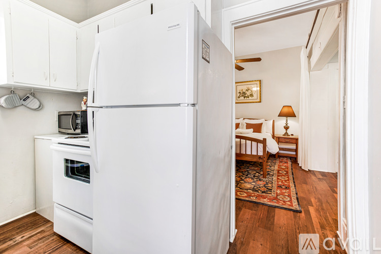 A white refrigerator is in a kitchen with a white oven and microwave.