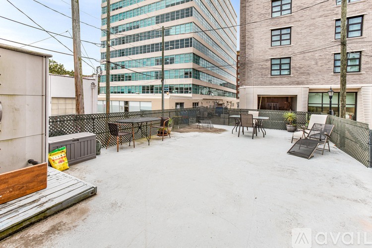 A backyard with a fence, a table and chairs, and a building in the background.