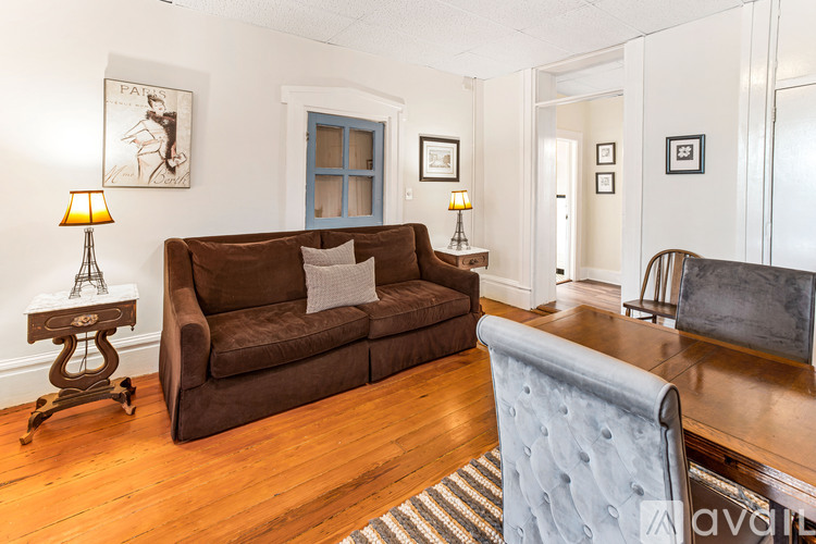 A brown couch sits in a living room with a blue chair in front of it.