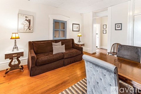 A brown couch sits in a living room with a blue chair in front of it.