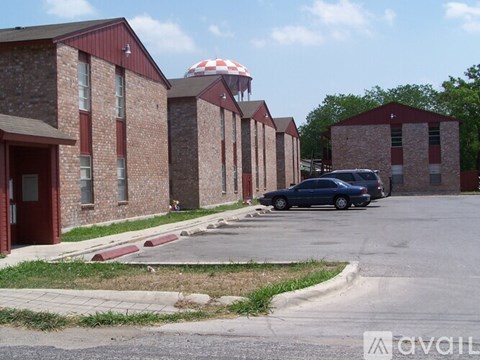 A car is parked in front of a brick building with a red and white striped umbrella.