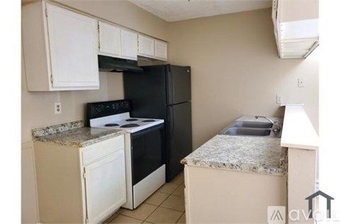 A kitchen with a black refrigerator, white cabinets, and a granite countertop.