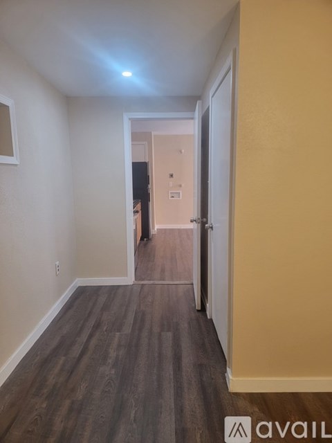 A long hallway with a light on the ceiling and a door at the end.
