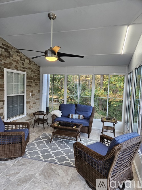 A patio with a ceiling fan and wicker furniture.