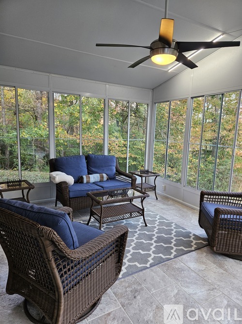 A sunroom with a ceiling fan and wicker furniture.