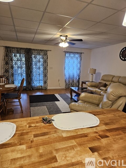 A living room with a brown wooden table in the foreground and a beige sofa in the background.