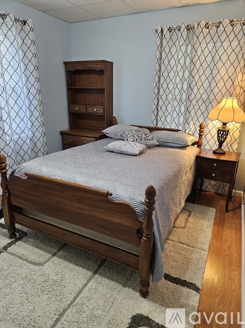 A bedroom with a bed, a nightstand with a lamp, and a wooden cabinet.