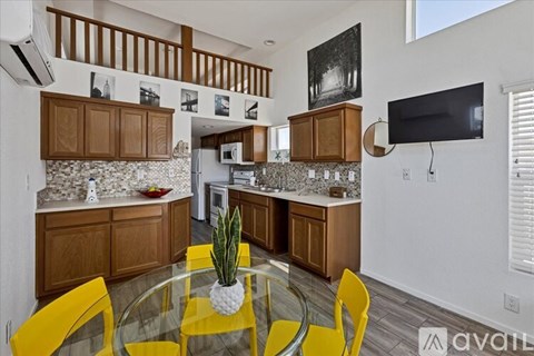 A kitchen with a glass table and yellow chairs.