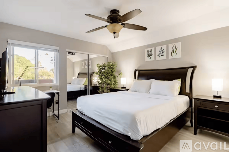 A bedroom with a large bed and a ceiling fan.