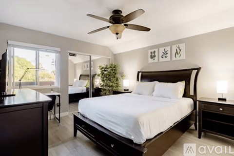 A bedroom with a large bed and a ceiling fan.