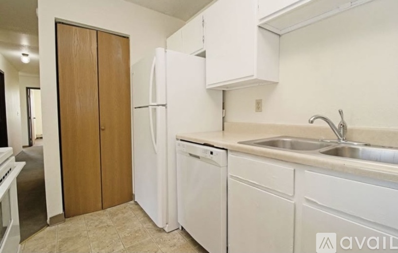 A kitchen with white appliances and a wooden door.