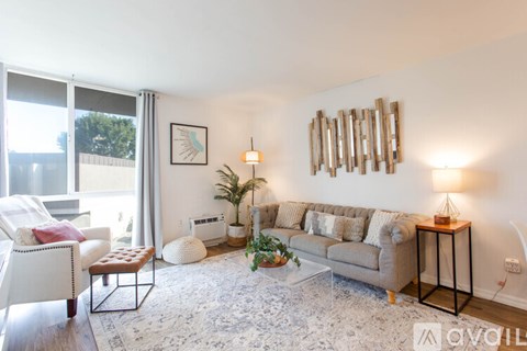 A living room with a couch, chair, and a table with a lamp on it.