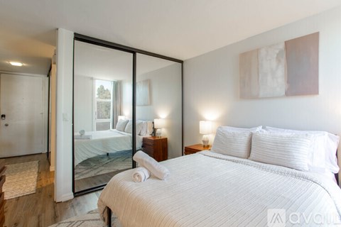 A bedroom with a large bed and a mirrored wall.