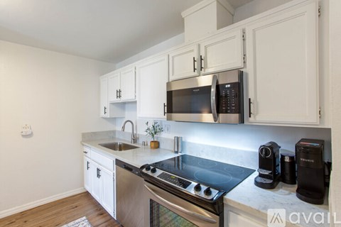 A kitchen with white cabinets and a stainless steel stove top.