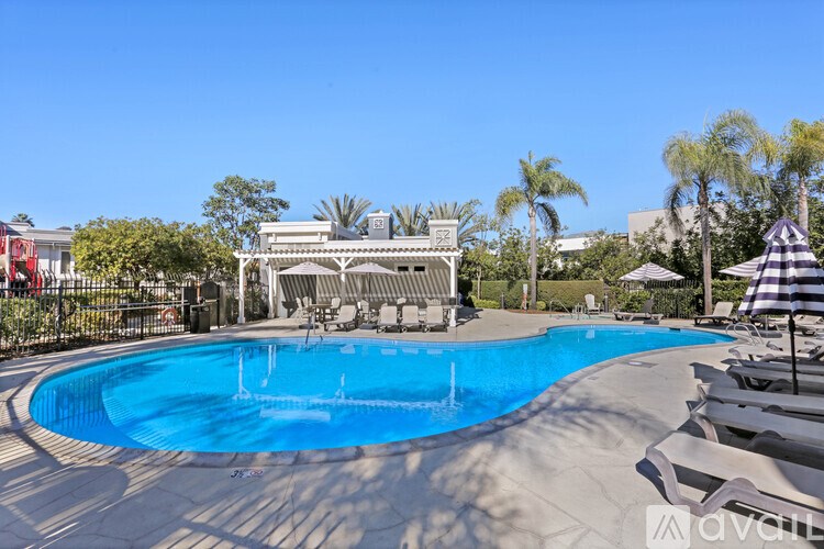 A large outdoor swimming pool surrounded by lounge chairs and umbrellas.