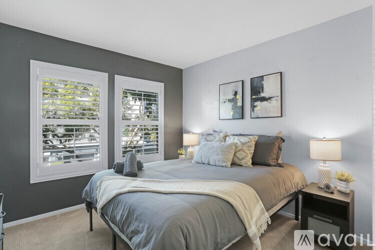 A bedroom with a large bed and two framed pictures on the wall.