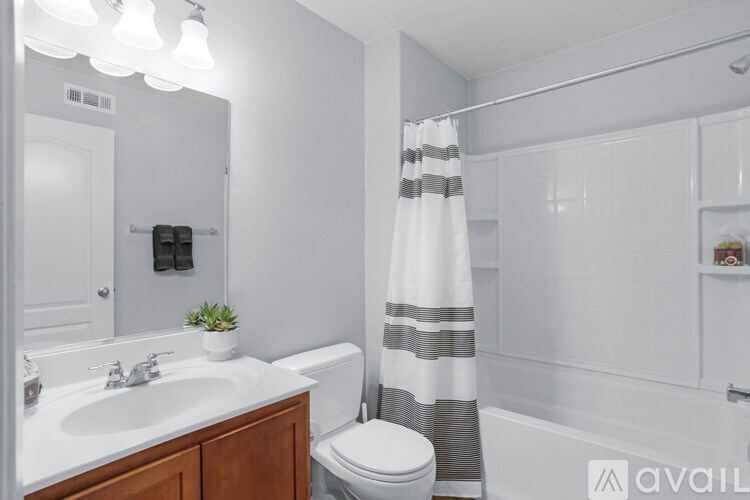 A bathroom with a white sink, toilet, and shower curtain.