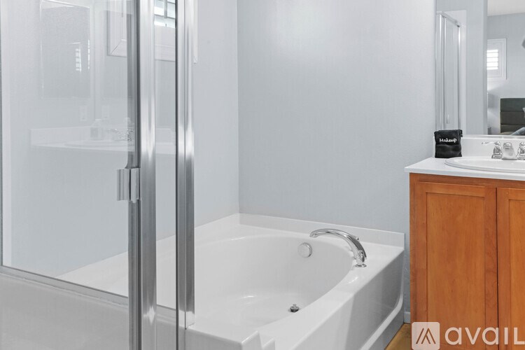A white bathtub with a glass shower door in a bathroom.