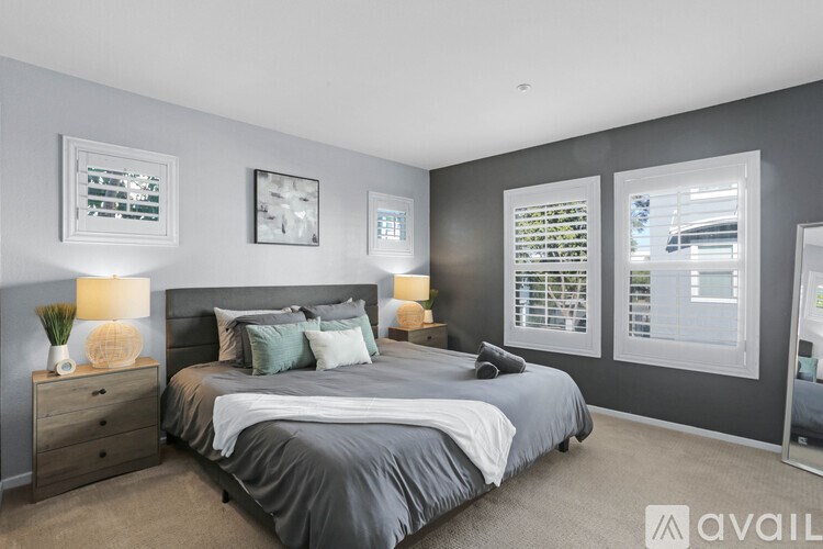 A bedroom with a large bed and a window with blinds.